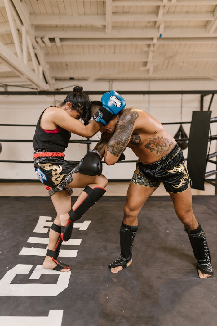 Two athletes engaged in a kickboxing training session in a gym. Intense focus and action.